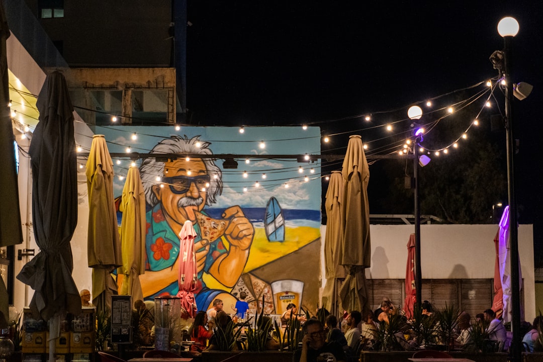 Outdoor cafe with mural and string lights at night